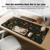 Dark botanical desk mat options with frogs, mushrooms, ferns, and acorns in brown and green tones, plus a matching keyboard wrist rest.