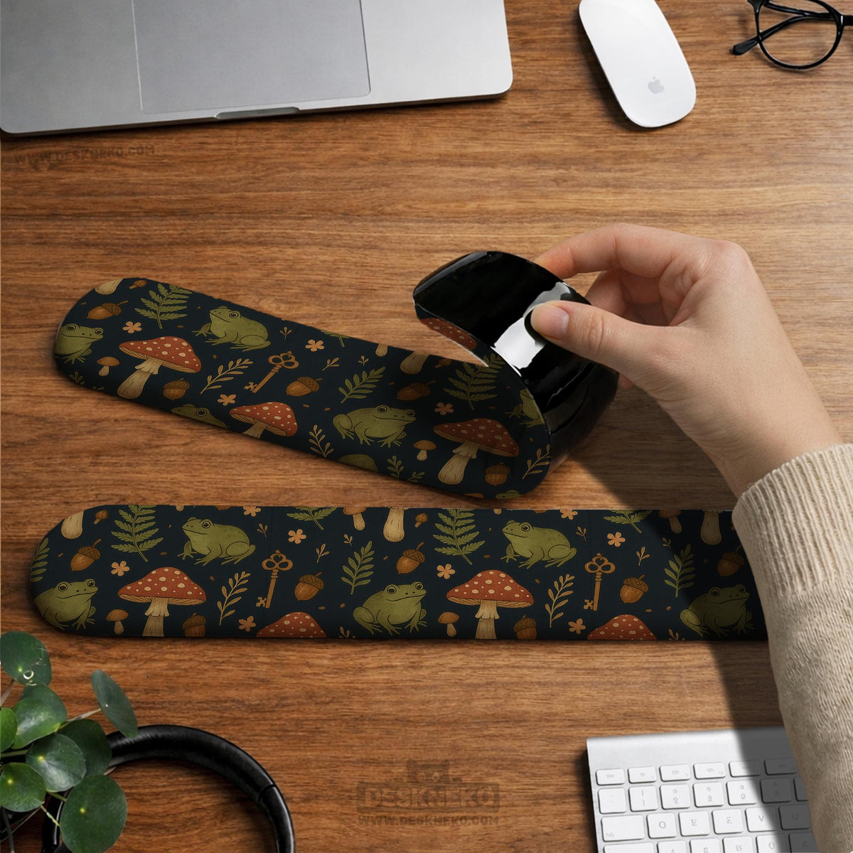 Dark botanical desk mat options with frogs, mushrooms, ferns, and acorns in brown and green tones, plus a matching keyboard wrist rest.
