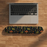 Dark botanical desk mat options with frogs, mushrooms, ferns, and acorns in brown and green tones, plus a matching keyboard wrist rest.