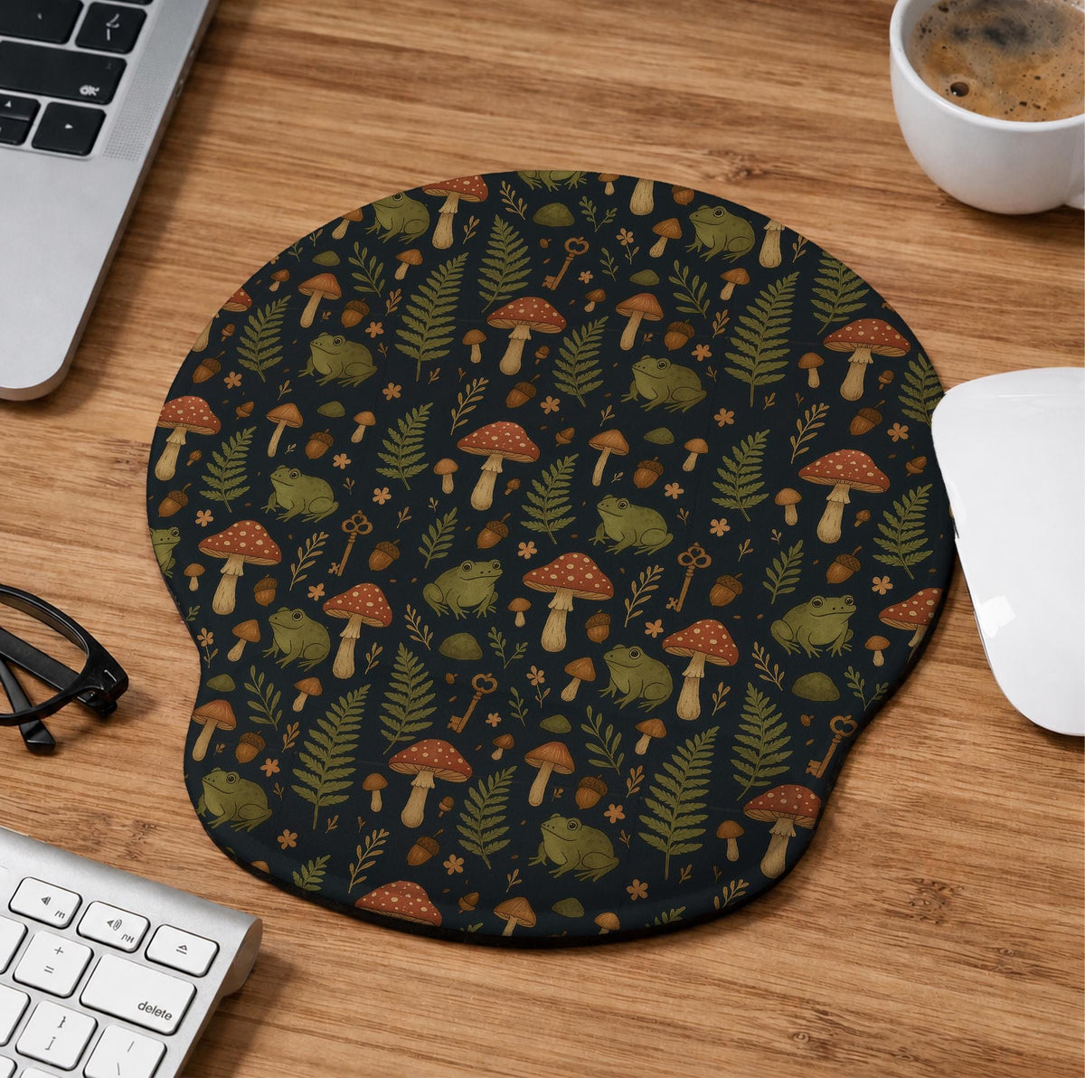 Dark botanical desk mat options with frogs, mushrooms, ferns, and acorns in brown and green tones, plus a matching keyboard wrist rest.