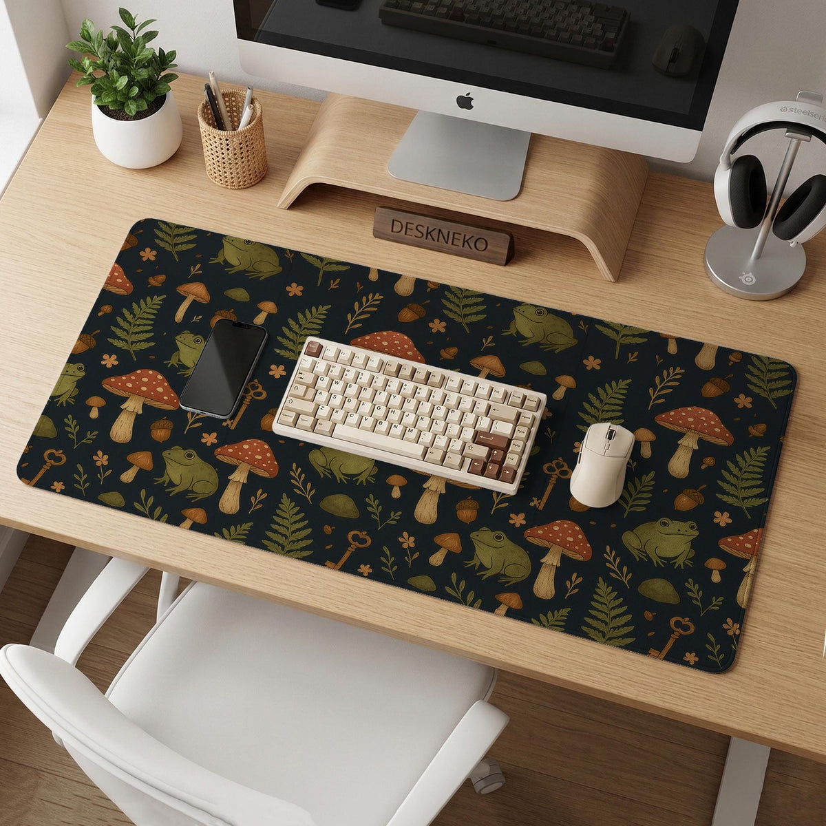Dark forest-themed desk mat with an all-over pattern of frogs, mushrooms, fern leaves, acorns, tiny flowers, and antique keys.