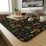 Dark forest-themed desk mat with an all-over pattern of frogs, mushrooms, fern leaves, acorns, tiny flowers, and antique keys.