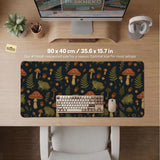 Dark forest-themed desk mat with an all-over pattern of frogs, mushrooms, fern leaves, acorns, tiny flowers, and antique keys.