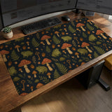 Dark forest-themed desk mat with an all-over pattern of frogs, mushrooms, fern leaves, acorns, tiny flowers, and antique keys.