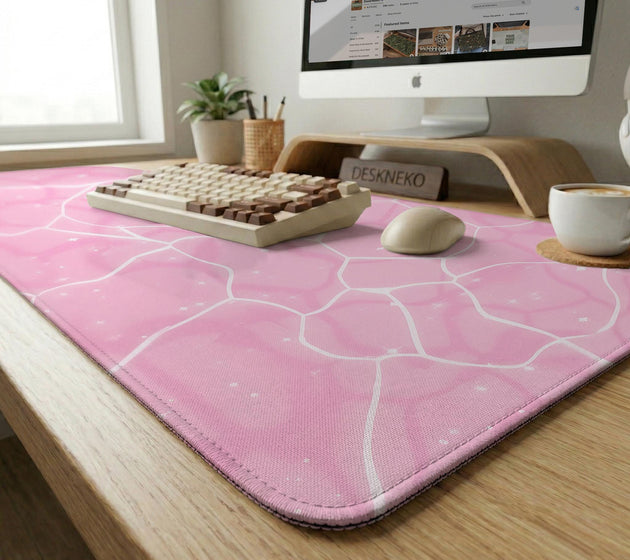 Pastel pink desk mat with a marble-style design, white flowing lines, and small sparkle accents.