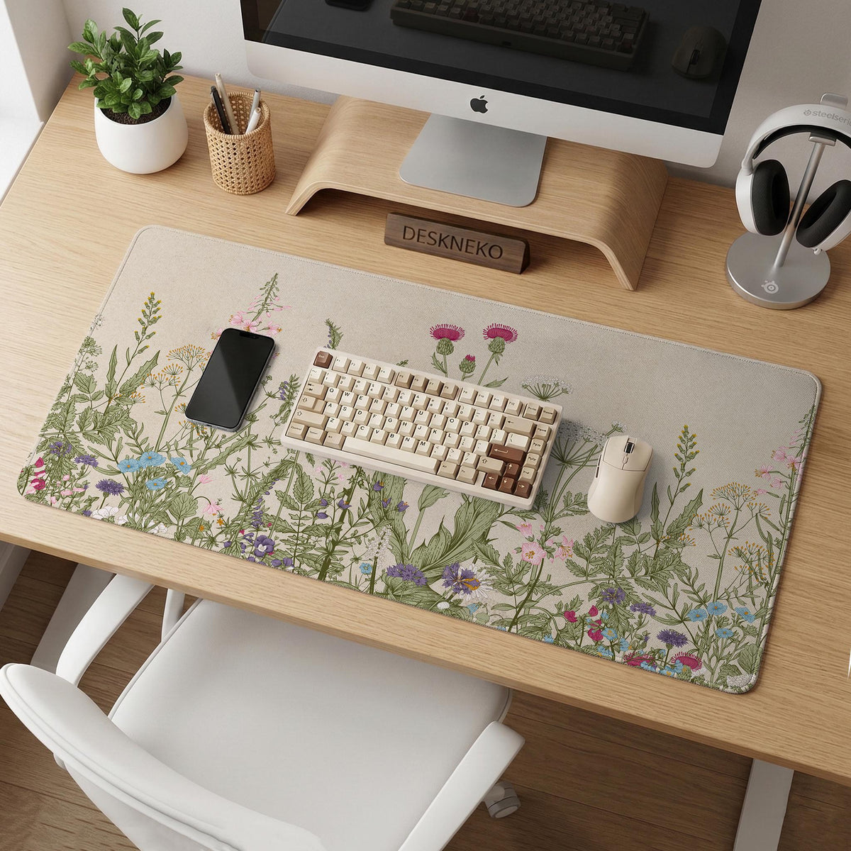 A desk mat with a botanical meadow design featuring wildflowers, leafy stems, and soft neutral colors.