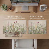 A desk mat with a botanical meadow design featuring wildflowers, leafy stems, and soft neutral colors.