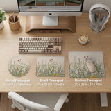 A desk mat with a botanical meadow design featuring wildflowers, leafy stems, and soft neutral colors.