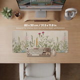 A desk mat with a botanical meadow design featuring wildflowers, leafy stems, and soft neutral colors.