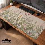 A desk mat with a botanical meadow design featuring wildflowers, leafy stems, and soft neutral colors.