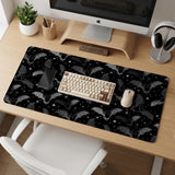 Black desk mat with a dark bat pattern and scattered stars on a charcoal background.