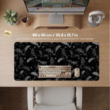 Black desk mat with a dark bat pattern and scattered stars on a charcoal background.