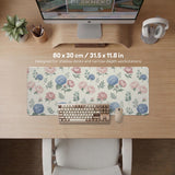Floral desk mat with sage greenery, pink peonies, blue flowers, and a warm cream background.