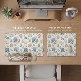 Floral desk mat with sage greenery, pink peonies, blue flowers, and a warm cream background.