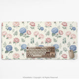 Floral desk mat with sage greenery, pink peonies, blue flowers, and a warm cream background.