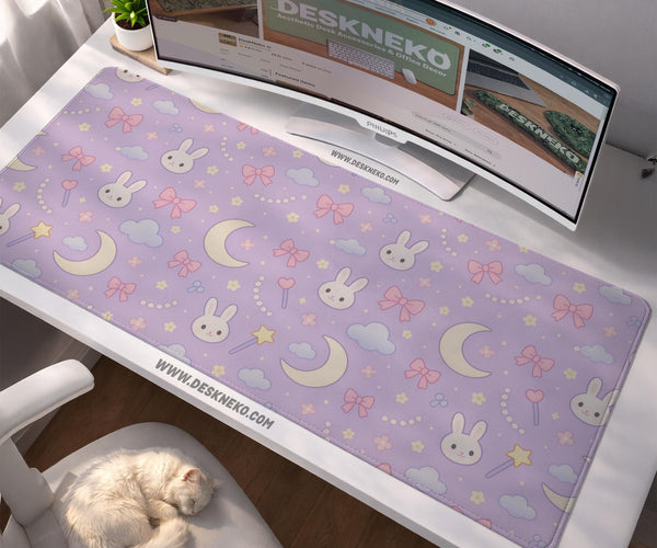 Lavender desk mat with an all-over pattern of bunny faces, clouds, moons, bows, and flowers in pastel colors.