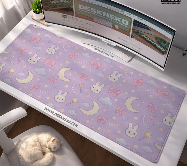 Lavender desk mat with an all-over pattern of bunny faces, clouds, moons, bows, and flowers in pastel colors.