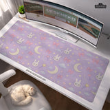 Lavender desk mat with an all-over pattern of bunny faces, clouds, moons, bows, and flowers in pastel colors.