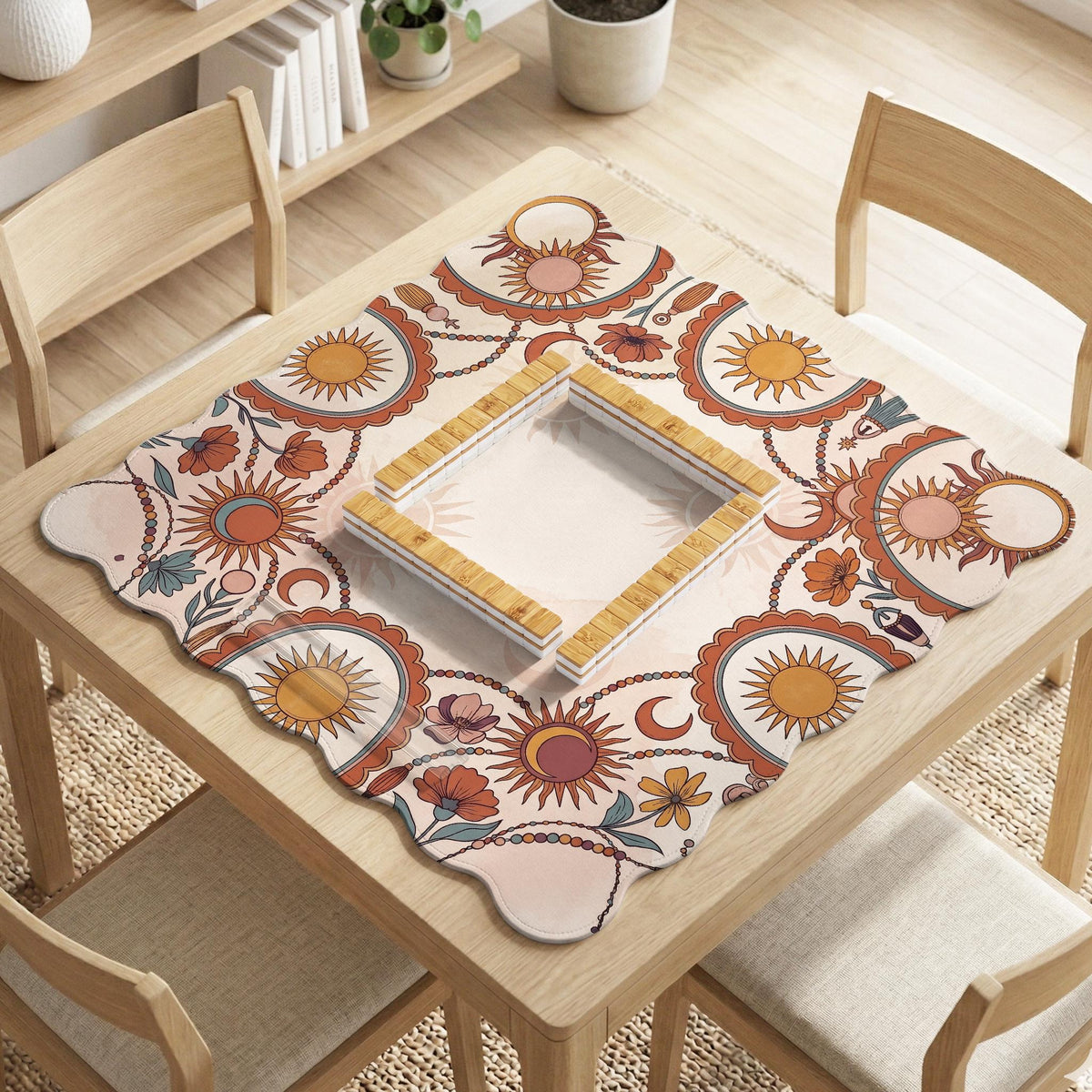 A square mahjong mat with a scalloped edge, sun and moon artwork, terracotta flowers, a soft cream background, and a decorative border around the play area.