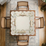 Square mahjong mat with a light floral border in sage green, cream, and blush around a plain center play area.