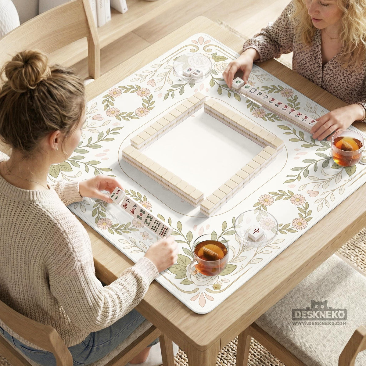 Square mahjong mat with a light floral border in sage green, cream, and blush around a plain center play area.