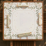 Square mahjong mat with a light floral border in sage green, cream, and blush around a plain center play area.