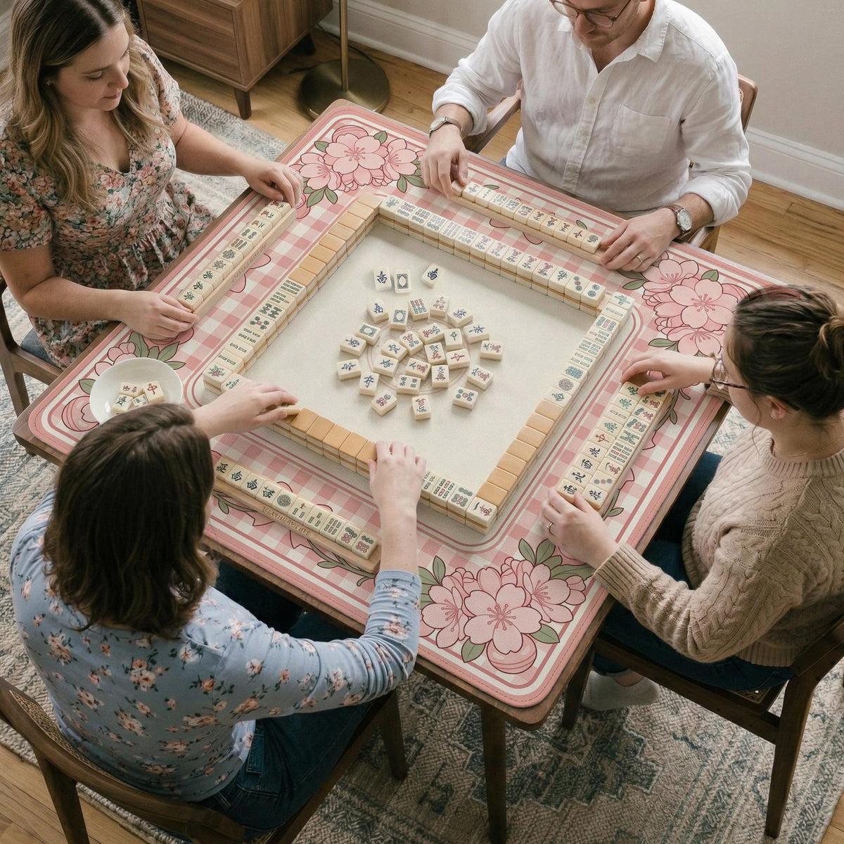 Pink gingham mahjong mat with a floral border, cherry blossom details, and a bow design around a plain center play area.