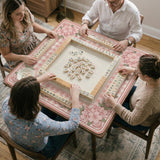 Pink gingham mahjong mat with a floral border, cherry blossom details, and a bow design around a plain center play area.
