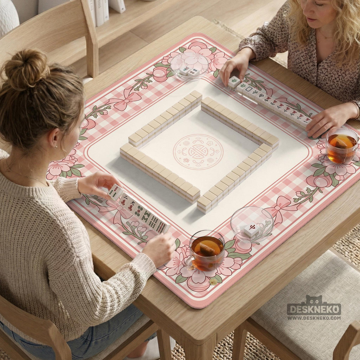 Pink gingham mahjong mat with a floral border, cherry blossom details, and a bow design around a plain center play area.