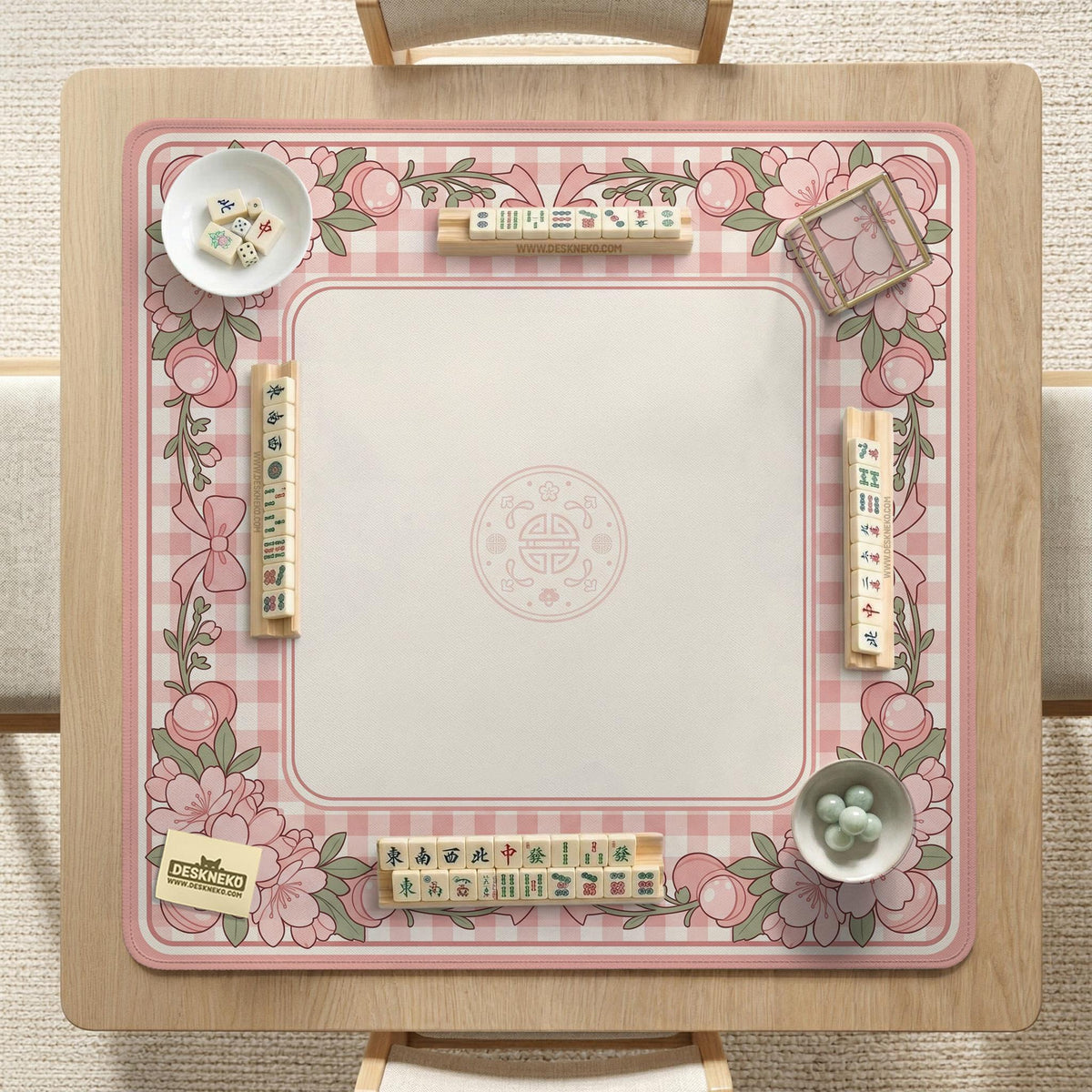 Pink gingham mahjong mat with a floral border, cherry blossom details, and a bow design around a plain center play area.