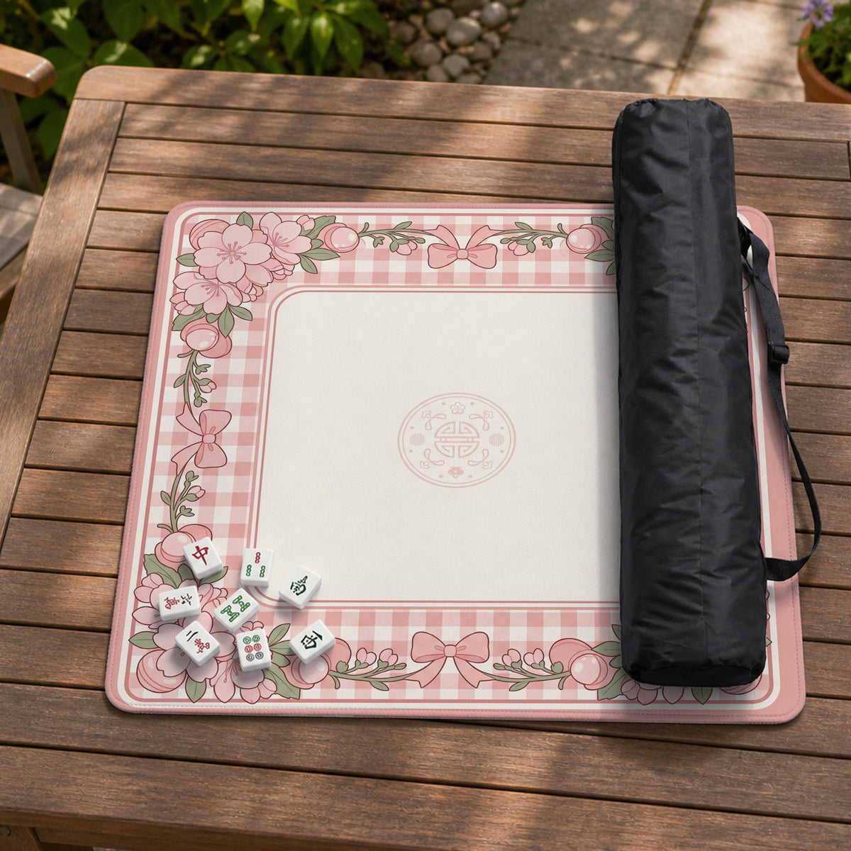 Pink gingham mahjong mat with a floral border, cherry blossom details, and a bow design around a plain center play area.