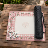 Pink gingham mahjong mat with a floral border, cherry blossom details, and a bow design around a plain center play area.