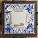 Square blue and white mahjong mat with peonies, cranes, pagoda accents, and chinoiserie linework around a plain center.