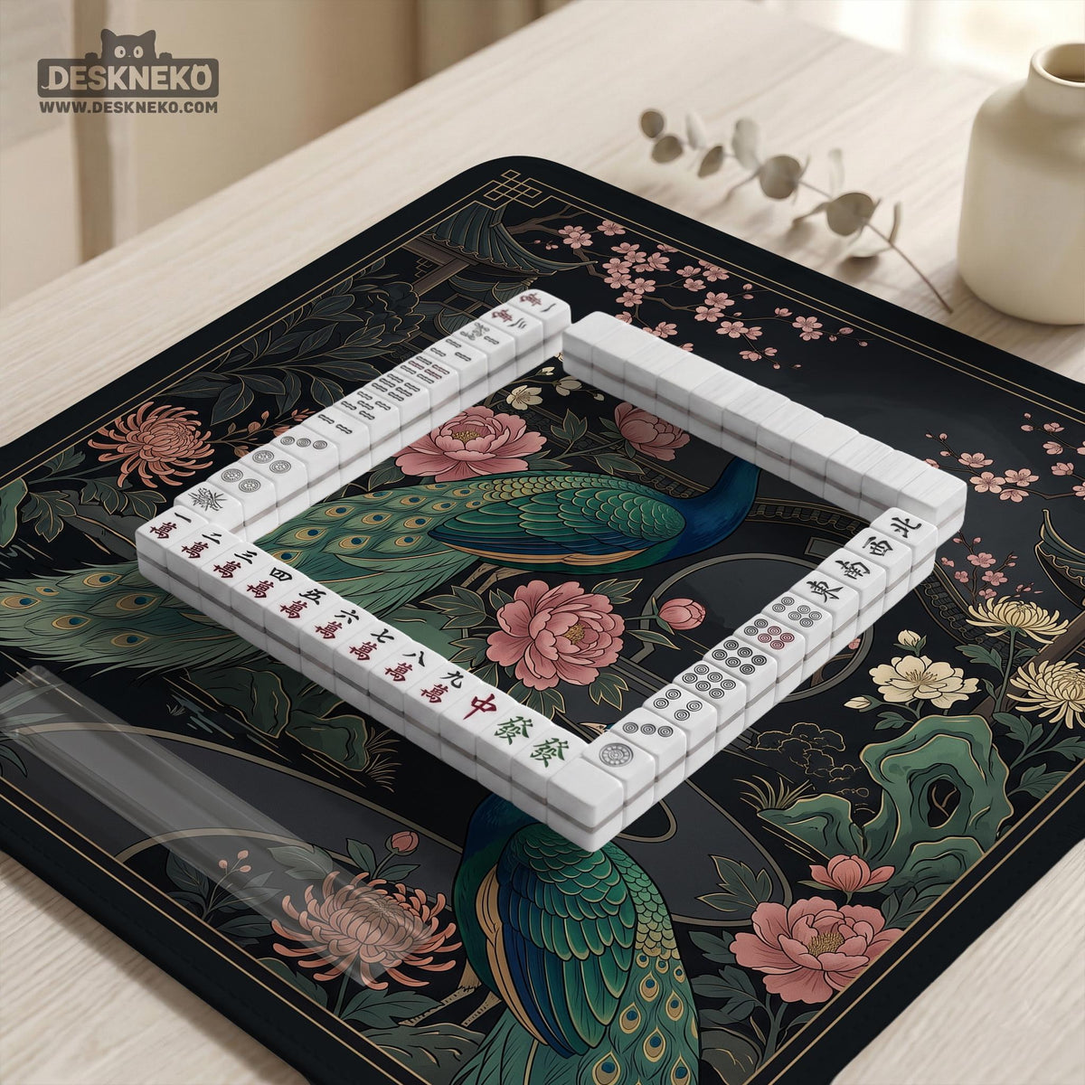 Square black mahjong mat with a gold peacock, blush flowers, and dark botanical artwork on a dark background.