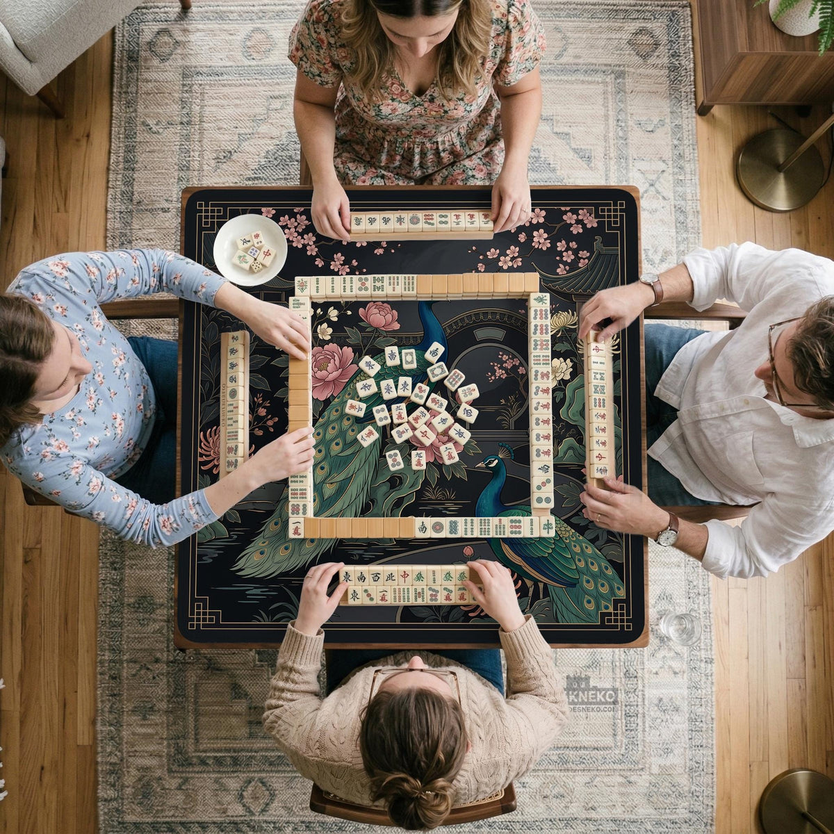 Square black mahjong mat with a gold peacock, blush flowers, and dark botanical artwork on a dark background.