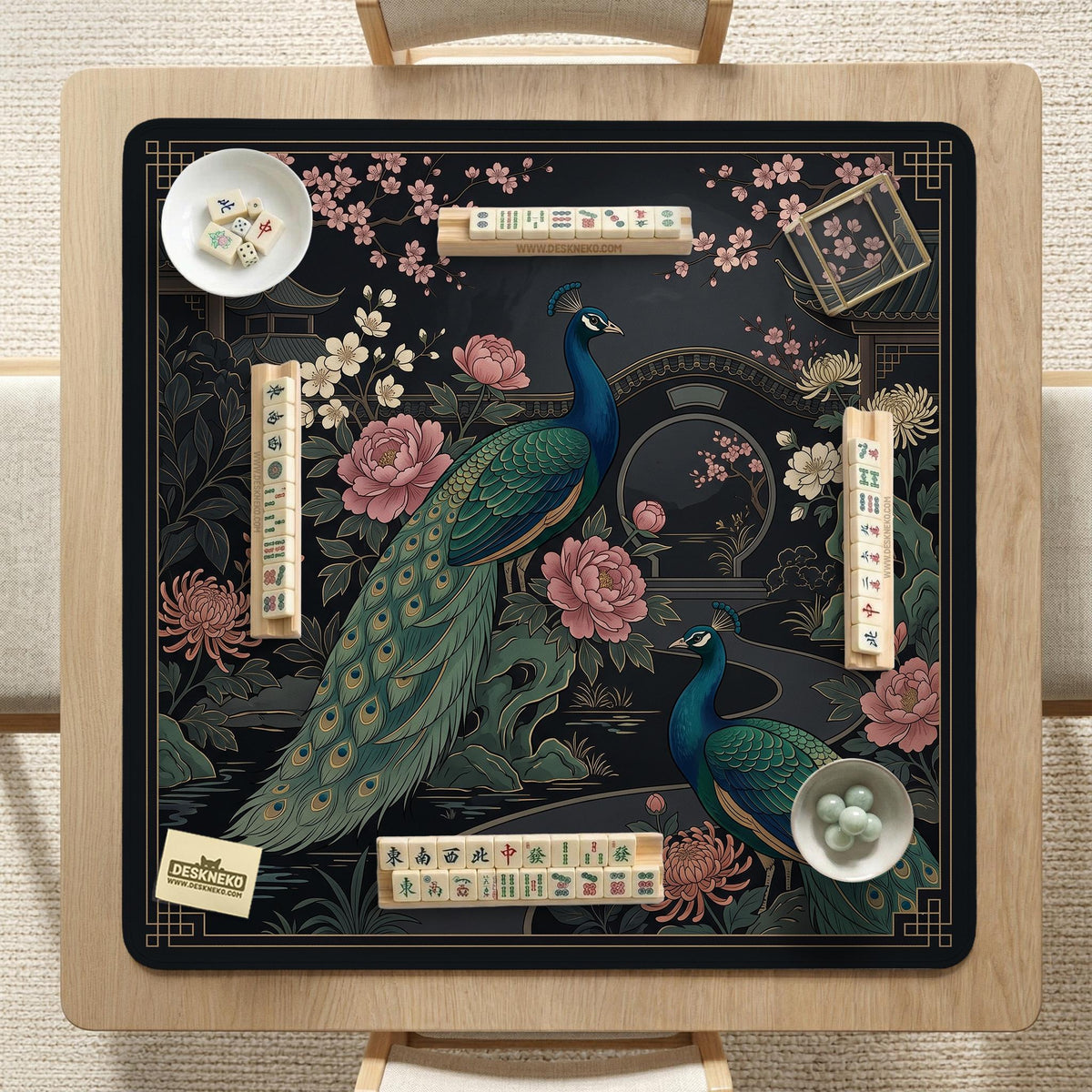 Square black mahjong mat with a gold peacock, blush flowers, and dark botanical artwork on a dark background.
