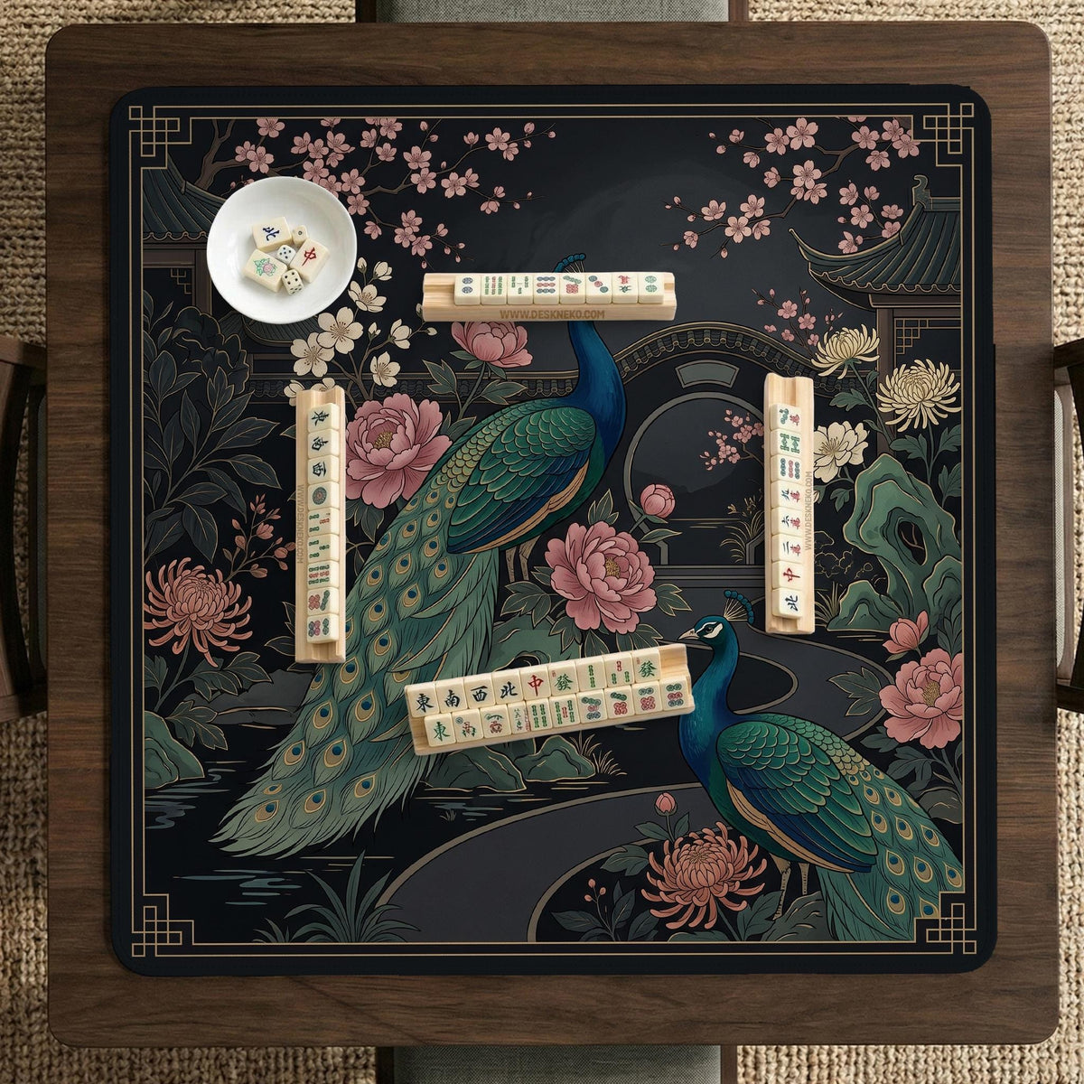 Square black mahjong mat with a gold peacock, blush flowers, and dark botanical artwork on a dark background.