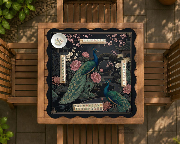 Square black mahjong mat with a gold peacock, blush flowers, and dark botanical artwork on a dark background.