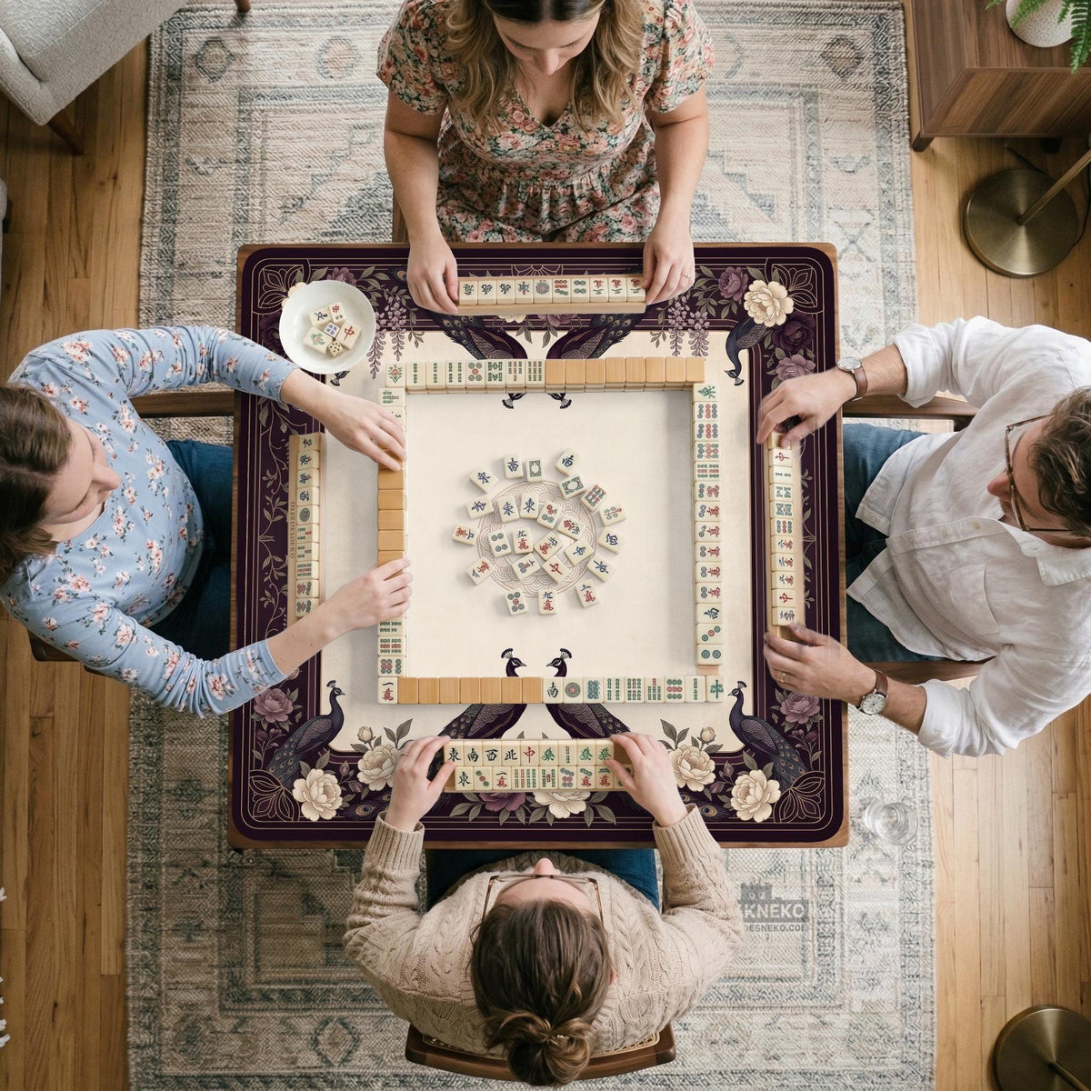 Square mahjong mat with a dark plum border, ivory floral pattern, muted sage leaves, and a decorative peacock garden design.