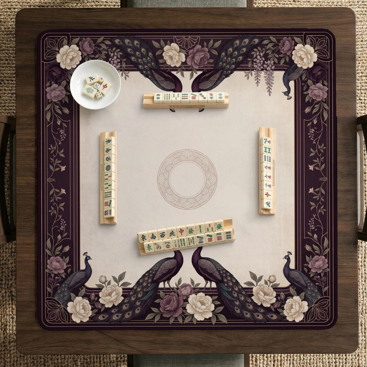 Square mahjong mat with a dark plum border, ivory floral pattern, muted sage leaves, and a decorative peacock garden design.