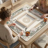 Square mahjong table mat with a cream center and a border design of cranes, bamboo, plum blossoms, and a geometric frame in sage green and warm gold.