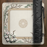 Square mahjong table mat with a cream center and a border design of cranes, bamboo, plum blossoms, and a geometric frame in sage green and warm gold.