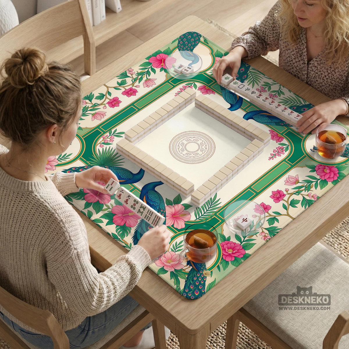 Green mahjong mat with peacocks, hibiscus flowers, tropical leaves, cream center space, and a scalloped floral border.