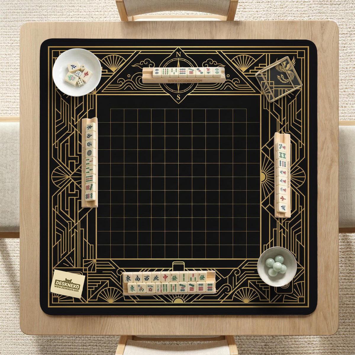 Black and gold square mahjong mat with a scalloped edge, geometric border, thin line details, fan motifs, and dragon and phoenix accents around an open center.