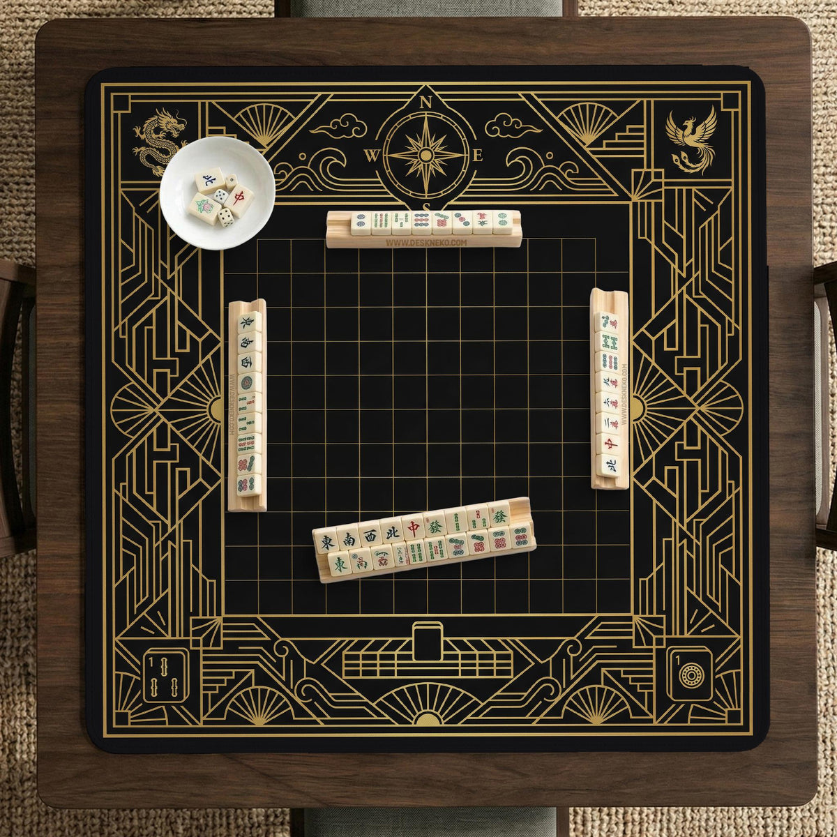Black and gold square mahjong mat with a scalloped edge, geometric border, thin line details, fan motifs, and dragon and phoenix accents around an open center.