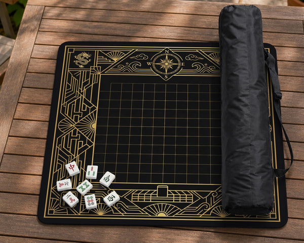 Black and gold square mahjong mat with a scalloped edge, geometric border, thin line details, fan motifs, and dragon and phoenix accents around an open center.
