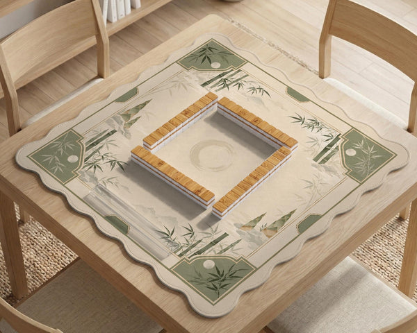 Square mahjong mat with a sage green bamboo and mountain design, cream center, scalloped border details, and gold line accents.