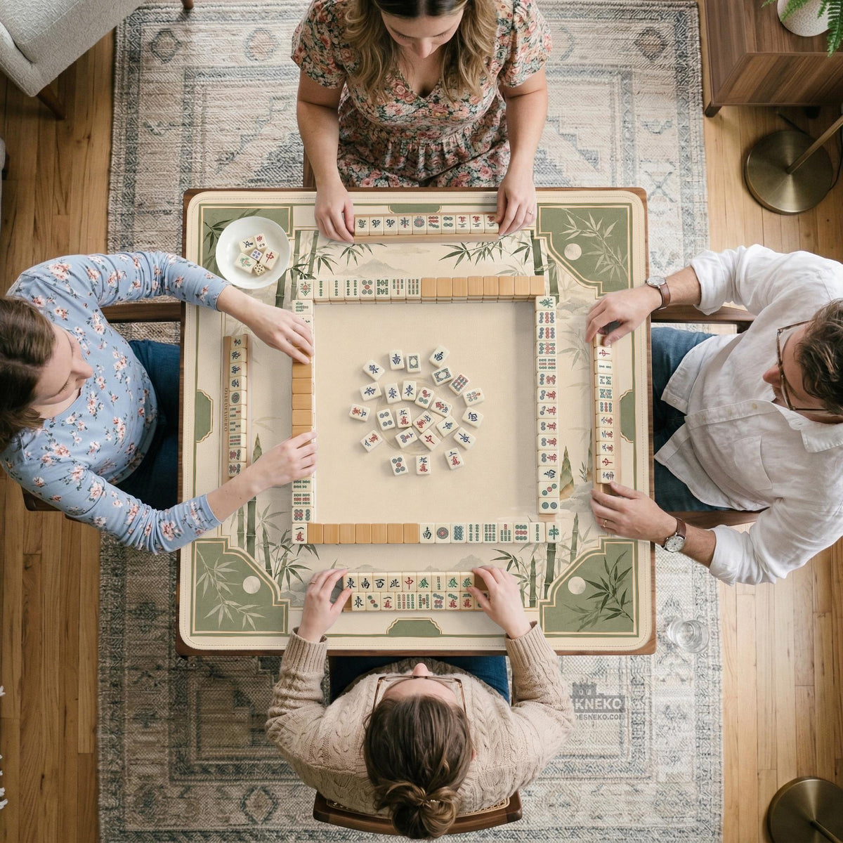 Square mahjong mat with a sage green bamboo and mountain design, cream center, scalloped border details, and gold line accents.