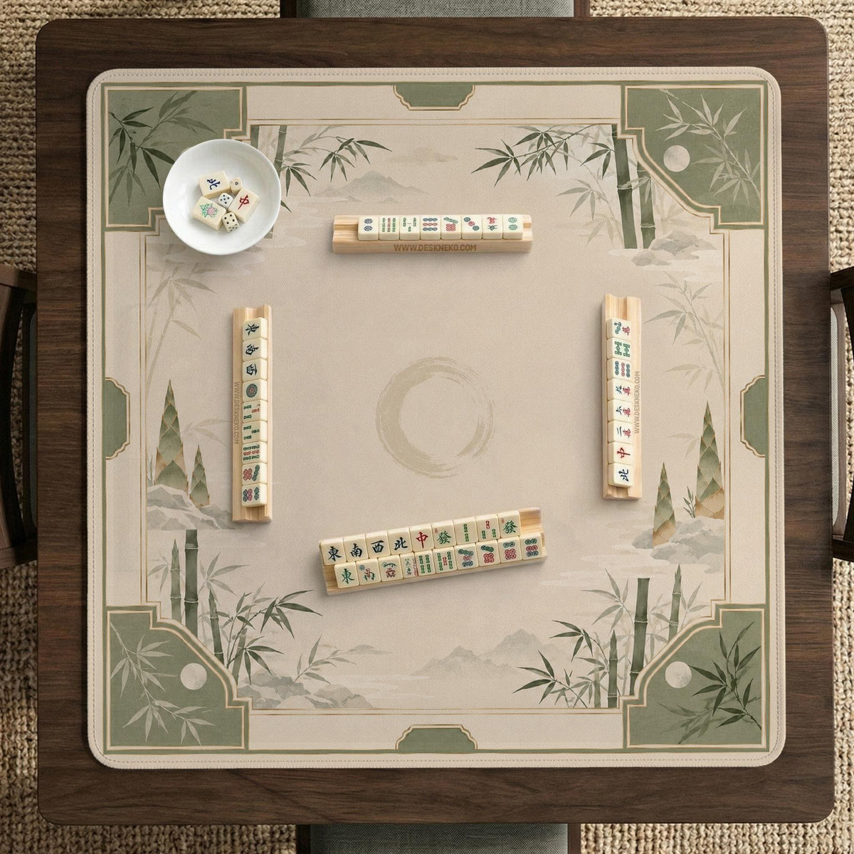 Square mahjong mat with a sage green bamboo and mountain design, cream center, scalloped border details, and gold line accents.