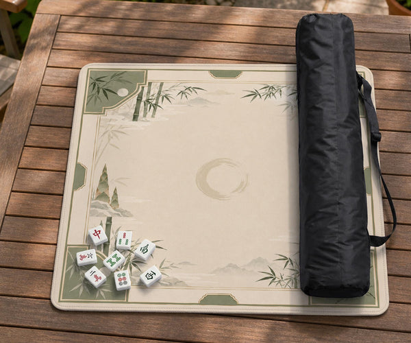 Square mahjong mat with a sage green bamboo and mountain design, cream center, scalloped border details, and gold line accents.